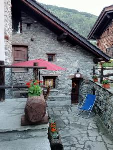 un edificio de piedra con sombrilla rosa y silla azul en Chalet in pietra, en Antey-Saint-André