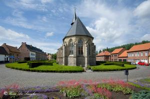 una iglesia con una torre de reloj en una ciudad en Begijnhof 54, en Sint-Truiden