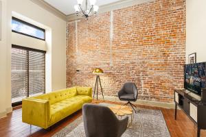 uma sala de estar com um sofá amarelo e uma parede de tijolos em Chuck's Place em Nova Orleans