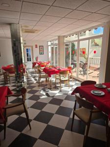 a restaurant with red tables and chairs and a checkered floor at Hotel Betania in Benalmádena