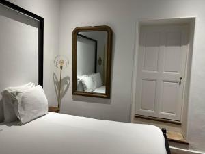 a bedroom with a white bed and a mirror at Domaine La Tour - SPA - Jacuzzi - Sauna - Massage - 4 SAISONS - Piscine Chauffée Toute l'année - Heated POOL - 800m City Centre Nyons in Nyons