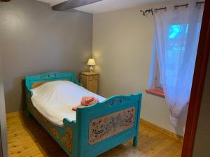 ein kleines Schlafzimmer mit einem blauen Bett und einem Fenster in der Unterkunft Ferme alsacienne in Soppe-le-Haut