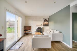 a living room with two white chairs and a tv at Maison avec piscine pour 8 - 500m de la plage in Plobannalec-Lesconil