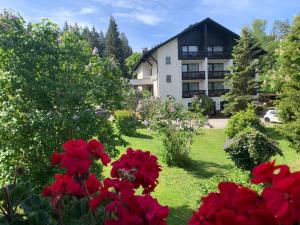 a view of a building with red flowers in a yard at Landhaus Am Forst in Bad Alexandersbad