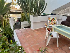 a patio with a table and a chair and cactus at Paradise PLAYA CHICA con terraza a 100m del Mar in Puerto del Carmen