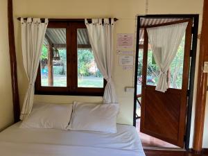 a bed in a room with a window and a door at Baan rabiang Pai บ้านระเบียงปาย in Pai