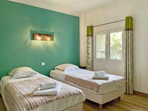 two beds in a room with green walls and a window at Château de la Motte in Marcorignan