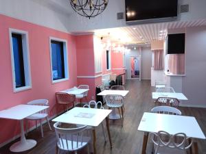 a dining room with tables and chairs and pink walls at Cafe&Hostel Kimi to Ichigo in Osaka