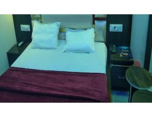 a bedroom with a large bed with white sheets and pillows at Govindham Hotel & Restaurant, Kurukshetra in Kurukshetra