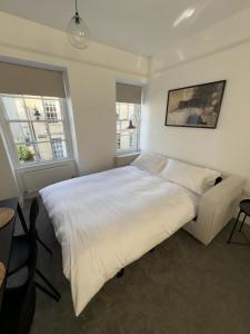 a bedroom with a large white bed and two windows at Kingsmead Square Apartments in Bath +13 photos