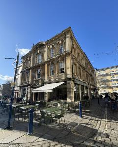 un ancien bâtiment avec des tables et des chaises devant lui dans l'établissement 2 Kingsmead Square, à Bath