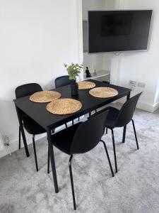 - une table à manger noire avec des chaises et une télévision dans l'établissement 2 Kingsmead Square, à Bath