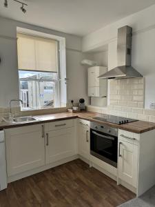 a kitchen with white cabinets and a sink and a stove at Kingsmead Square Apartments in Bath