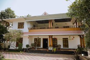 Großes weißes Haus mit Balkon in der Unterkunft Fool's Paradise in Alappuzha
