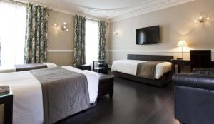 パリにあるホテル クロード ベルナール サン ジェルマンのベッド2台、薄型テレビが備わるホテルルームです。