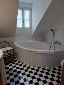 a white tub in a bathroom with a checkered floor at Gästehaus Hans Moser in Purbach am Neusiedlersee
