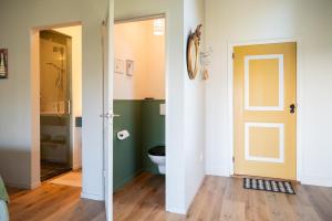 La salle de bains est pourvue de toilettes et d'une porte en verre. dans l'établissement Kleinhoef - charmante, luxe kamers in een boerderij uit 1875, à Nigtevecht