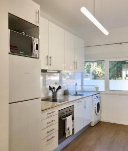 een witte keuken met een wastafel en een magnetron bij Feel Cascais Center 2bd in Cascais