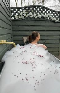 uma mulher sentada numa cama coberta de flores em Bodos’ Shepards Hut em Durham