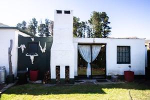 une maison blanche avec une porte avec des crânes de cerfs dessus dans l'établissement Clifford Selfcatering Guesthouse, à Barkly East