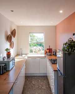 a kitchen with white cabinets and a window at Soutelande Eco-Hideaway - 2min Drive to Pristine Beach in Port Elizabeth