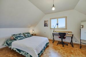 a bedroom with a bed and a desk and a window at Maison Boisée - Charmante maison au calme 