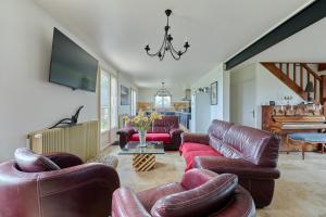 sala de estar con sofás de cuero y TV en Maison Boisée - Charmante maison au calme 