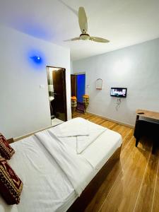 a bedroom with a large bed with a ceiling fan at Lotus Guest House in Kharakvasla