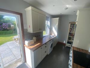 cocina con encimera, fregadero y ventana en Houghton Park Holiday Cottage en Newcastleton