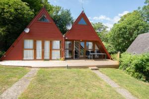a large red house with a wooden deck in a yard at Chalet 137 in Deal