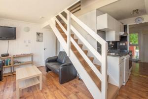 a living room with a staircase and a kitchen at Chalet 137 in Deal