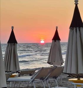 2 ligstoelen en parasols op het strand bij zonsondergang bij TamarHouse Sperlonga Casa Naila in Sperlonga
