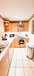 倫敦的住宿－London Docklands RiverSide Apartment，厨房配有木制橱柜和白色瓷砖地板。