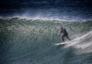 a man riding a wave on a surfboard in the ocean at 30 Degrees Beach Apartment Umdloti in Umdloti