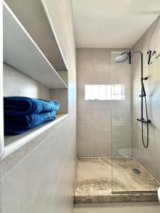 un bagno con doccia e asciugamani blu su una mensola di Blissapartments T2 - Simone (nearby the beach) a Mindelo