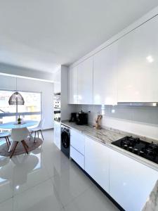 a kitchen with white cabinets and a table in it at Blissapartments T2 - Simone (nearby the beach) in Mindelo