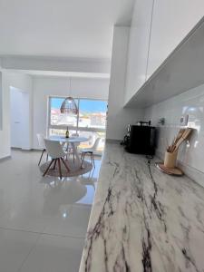 a white kitchen with a table and chairs in it at Blissapartments T2 - Simone (nearby the beach) in Mindelo