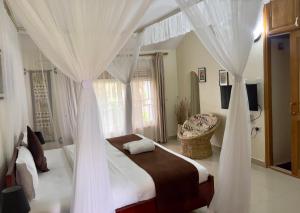 a bedroom with a canopy bed with white curtains at Sunset Hotel Entebbe in Entebbe