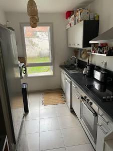 uma cozinha com bancadas pretas e uma janela em Maison proche ville olympique et stade de France em Saint-Denis