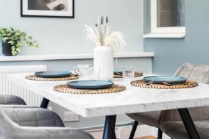 einen weißen Tisch mit blauen Platten und einer Vase in der Unterkunft Luxurious 3 Bedroom House with Parking 73B - Top Rated - Netflix - Wifi - Smart TV in Holly Lane