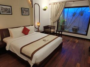 um quarto com uma cama grande e uma janela grande em THUY DUONG 3 Boutique Hotel & Spa em Hoi An