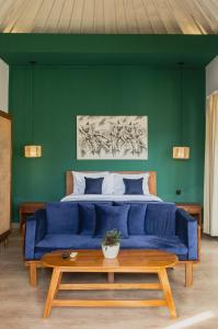 a blue couch in front of a green wall with a bed at Jetian villa in Nusa Lembongan