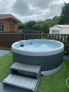 a hot tub with a bench in a yard at 23 Ocean View Lodge TJS 23875 in Ilfracombe