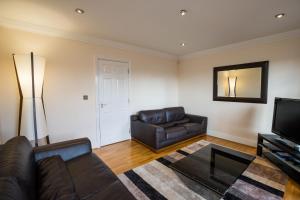 een woonkamer met een leren bank en een televisie bij Spacious, 3 Bed House for 6 in Central Chester in Chester