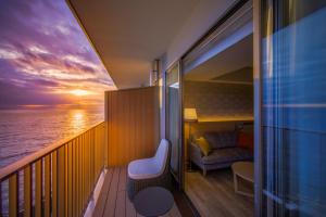 un balcón con una silla y un sofá en un barco en Atami Korakuen Hotel en Atami