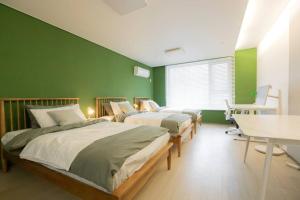2 camas en una habitación con paredes verdes en MIRAE_stay 52 New Open [1 Queen + 2 Single beds] en Seúl