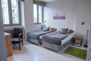 sypialnia z 2 łóżkami, krzesłem i oknami w obiekcie Republika Słoneczna w Poznaniu