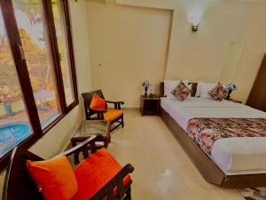 a hotel room with two beds and a chair at Shivam Resort With Swimming Pool ,Managed By The Four Season - 1 km from Calangute Beach in Goa