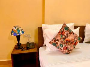 a bed with a pillow and a lamp on a table at Shivam Resort With Swimming Pool ,Managed By The Four Season - 1 km from Calangute Beach in Goa