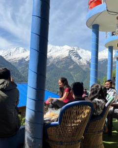 een groep mensen aan een tafel met bergen op de achtergrond bij Cafekush tosh in Tosh